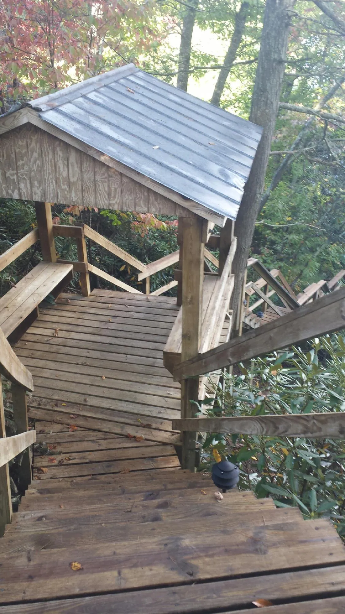 Metal roofed shelter over wooden steps on a wooded walkway — Skylight Repair & Installation work by our crew in Blacksburg